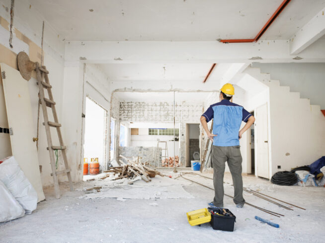 House renovation House improvement concept. Rear view of Asian construction worker looking away.